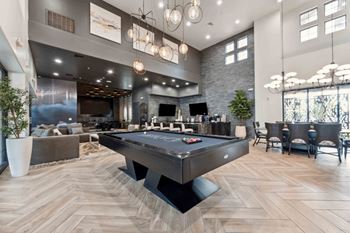 A pool table is in the middle of a room with a stone wall and a bar area. at The Laurel Apartments, Chandler, AZ 85286